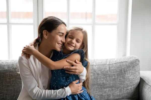 Happy small daughter hug smiling mom at home — Stock Photo, Image