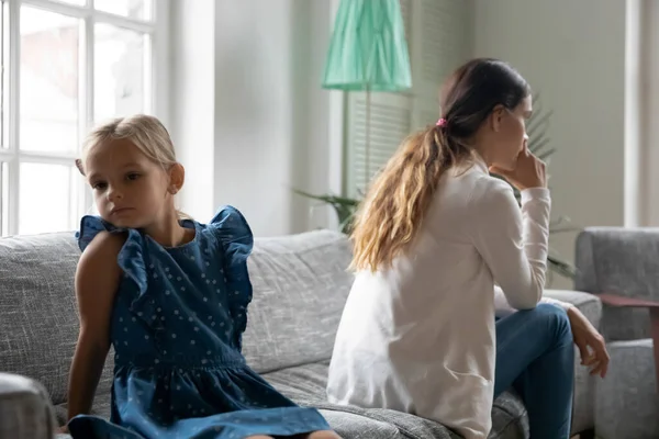 Unhappy mom and daughter sit back to back — стоковое фото