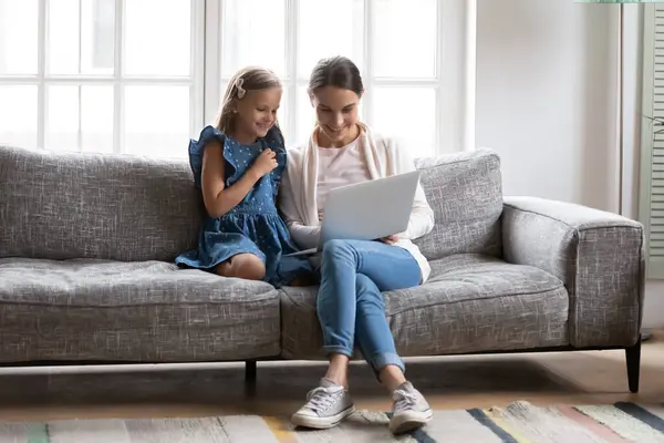 Sorrindo mãe e filha pequena usam laptop em casa — Fotografia de Stock