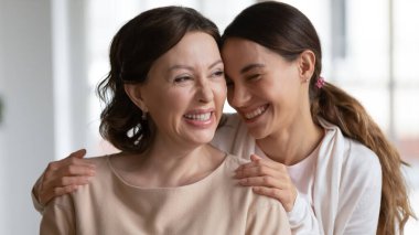 Mutlu, yetişkin bir kız, yaşlı bir anneye sarılıyor.
