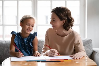 Mutlu büyükanne ve küçük torun birlikte çiziyorlar.