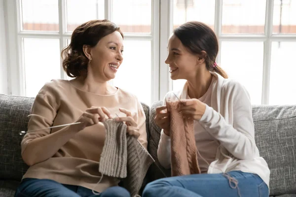 Happy old mom and adult daughter knit together — стоковое фото