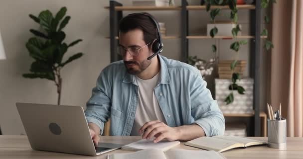 Enfocado joven en auriculares inalámbricos celebración de videollamada. — Vídeos de Stock