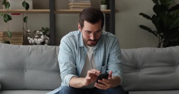 Jovem sonhador em óculos usando aplicativos para smartphones. — Vídeo de Stock