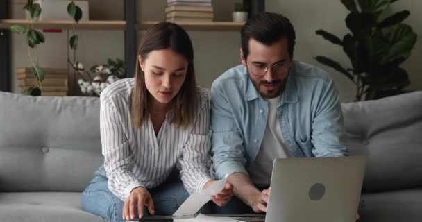 Geconcentreerd jong echtpaar dat de binnenlandse rekeningen berekent. — Stockvideo