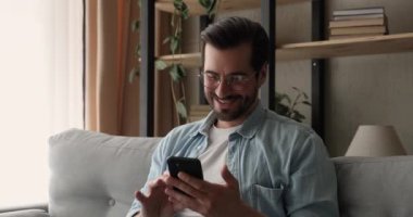 Mutlu genç adam akıllı telefon uygulamalarını kullanarak eğleniyor..