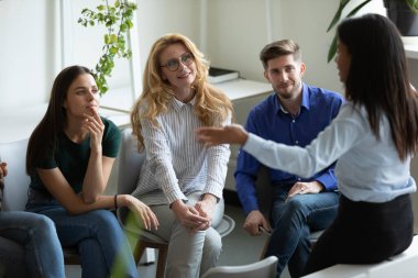 Farklı yaşlarda çalışanlardan oluşan bir iş ekibi kadın liderleri dinliyor.