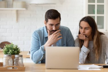 Ciddi endişeleri olan bir çift evde oturup laptoplara bakıyor.