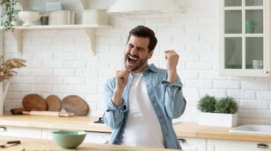 Elinde çırpıcı olan adam mutfakta şarkı söyleyerek ağzını açıyor.