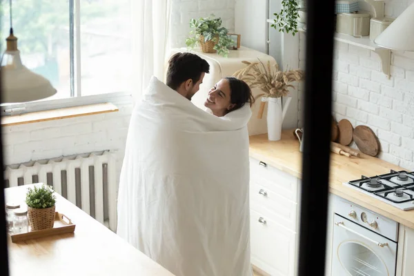 Sevgili çift modern mutfakta battaniyeye sarılı duruyor.