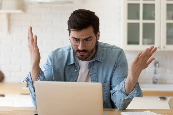 Homem irritado olhando para a tela do laptop com problemas com o dispositivo — Fotografia de Stock