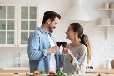 Kırmızı şarap kadehlerini kaldıran çiftler yeni evlerini mutfakta kutluyorlar.