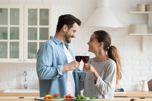 Paar heffende glazen rode wijn vieren housewarming in de keuken — Stockfoto