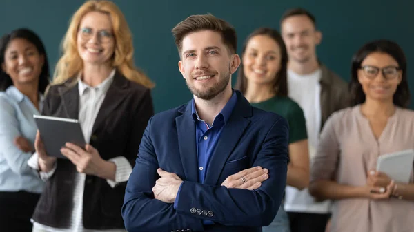 Happy male business leader posing with team in blurred background — Stock Photo, Image