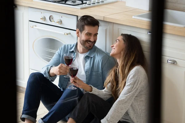 Couple assis sur le sol dans la cuisine cliquetis verres de vin — Photo