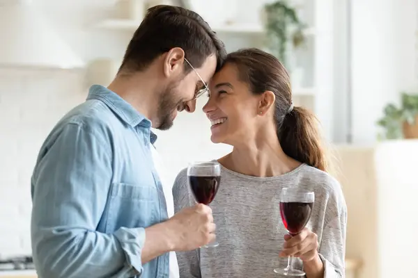 Şarap bardakları tutan sevgili çift alınlarına dokunuyor romantik bir buluşma. — Stok fotoğraf