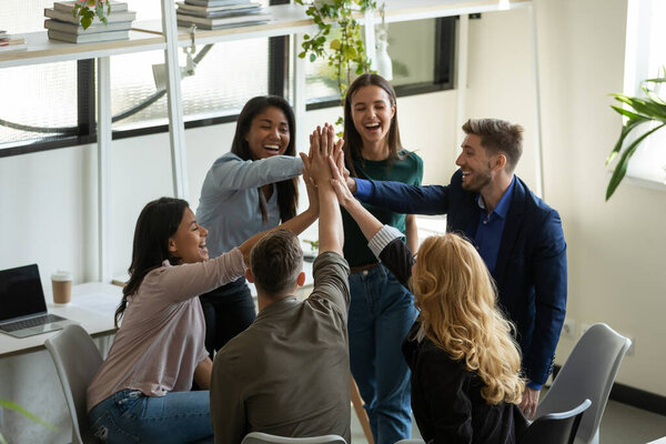 Happy overjoyed mixed race millennial team celebrating success