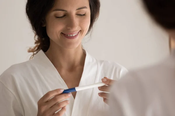 Glad young latin woman stand by mirror hold pregnancy test — Stock Photo, Image