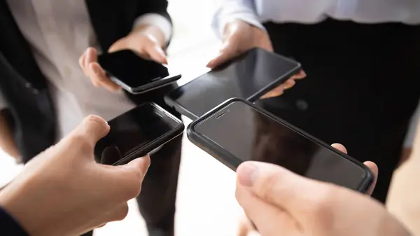 Grupo empresarial de pie en círculo, manteniendo juntos teléfonos móviles similares — Foto de Stock