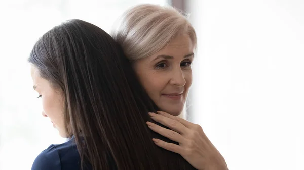 Sorrindo mãe madura pensativa e adulto filha reunião e abraço — Fotografia de Stock