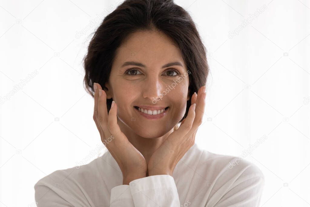 Pretty young latin woman looking at camera smiling touching cheeks