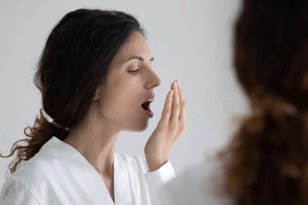 Young female testing breath smelling air holding palm by lips — Stock Photo, Image