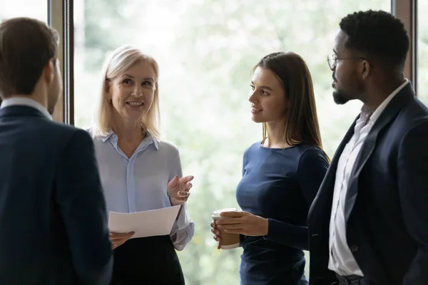 Gelukkig zelfverzekerde volwassen zakenvrouw, vrouwelijke leider, mentor instrueren divers team — Stockfoto