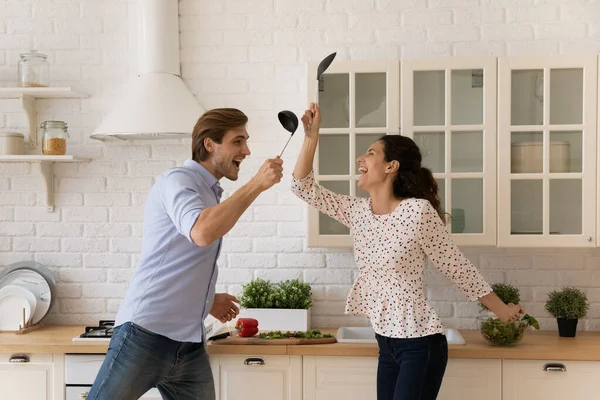 Skrattande makar som har kul i köket slåss på galet humör — Stockfoto