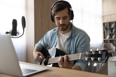 Gitar çalan, çevrimiçi kurslara çalışan odaklanmış bir genç..