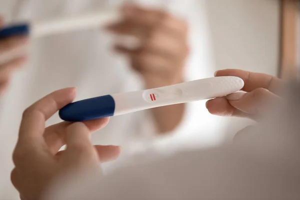 Millennial female hands holding domestic pregnancy test showing positive result — Stock Photo, Image