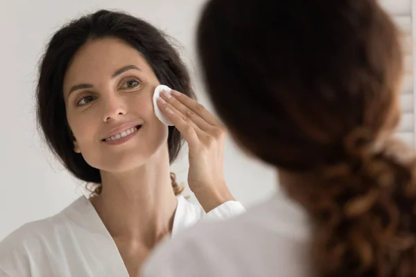 Jovem hispânico feminino remover maquiagem por espelho usando esponja — Fotografia de Stock