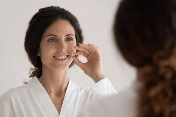 Smiling millennial hispanic lady hold yellow pill vitamin dietary supplement — Stock Photo, Image