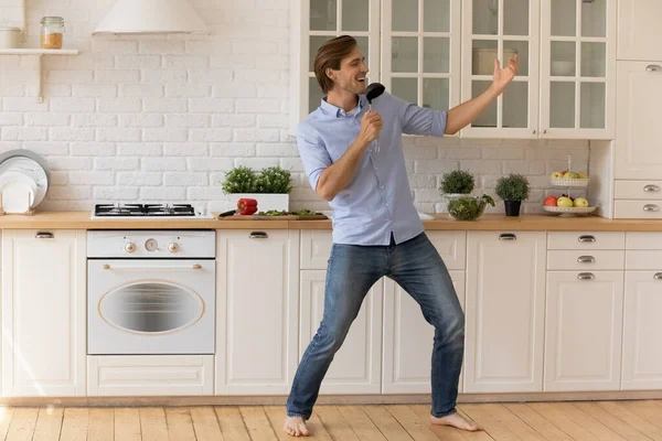 Inspirerad ung man står på varmt köksgolv sjunga högt — Stockfoto