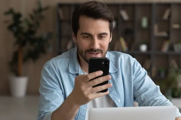 Sorrindo jovem empresário usando smartphone no escritório. — Fotografia de Stock