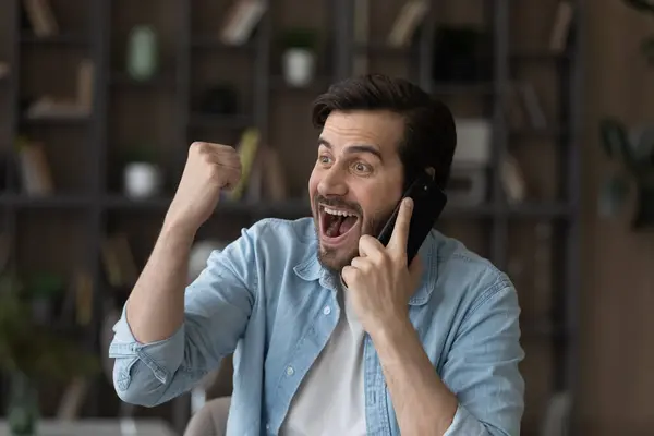 Ehrlicher emotionaler Jungunternehmer teilt Erfolg per Telefonanruf. — Stockfoto