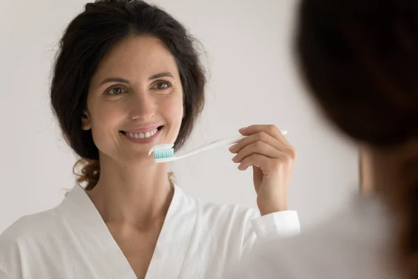 Jovem latina olhando espelho preparando-se para limpar os dentes — Fotografia de Stock