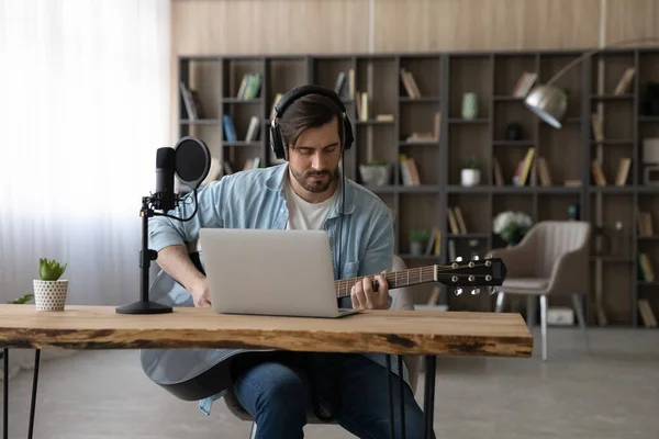 Focused young man in headphones playing guitar in home studio. — Stock Photo, Image