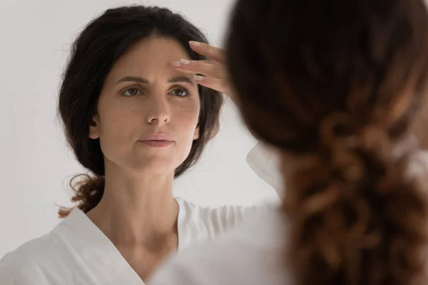 Young latin woman look at mirror see acne on face — Stock Photo, Image