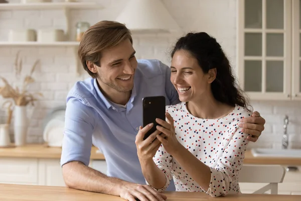 Ευτυχισμένο χαρούμενο οικογενειακό ζευγάρι που κοιτάζει την οθόνη smartphone διασκεδάζοντας — Φωτογραφία Αρχείου