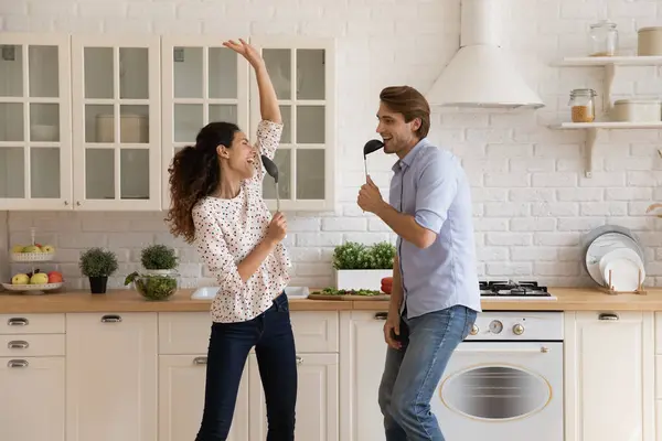 Playful young couple prepare food at kitchen enjoy singing songs — Stock Photo, Image