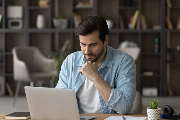 Concentrado millennial homem trabalhando no computador em casa escritório. — Fotografia de Stock