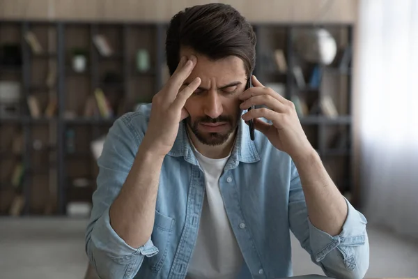 Gestresster junger Mann mit Handygesprächen im Amt. — Stockfoto