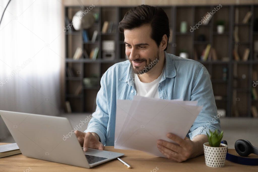 Happy young businessman working with documents on computer.