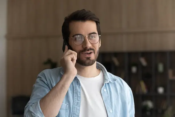 Happy young man in eyeglasses holding cellphone conversation. — Stock Photo, Image
