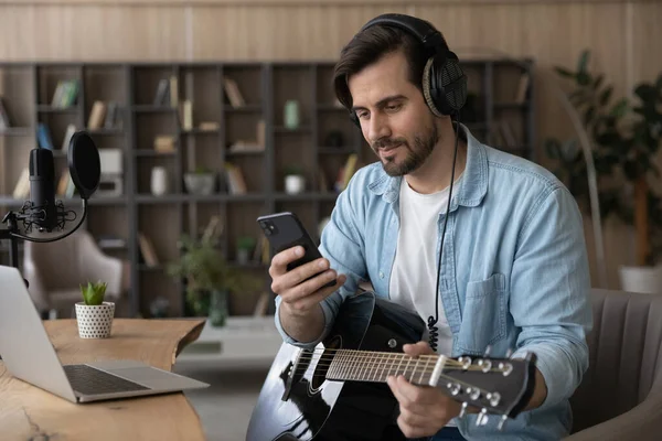 Distracted from practicing music happy young musician using smartphone. — Stock Photo, Image