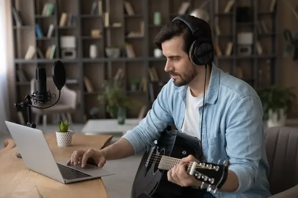 Happy young man playing guitar using computer application. — Stock Photo, Image