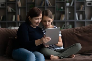 Mutlu son sınıf büyükanne ve tablet kullanan tatlı torun.