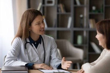 Yaşlı orta yaşlı hasta, genç bayan doktora danışmanlık yapıyor.