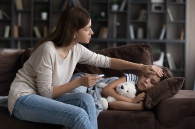 Endişeli anne kızının vücut ısısını kontrol ediyor.