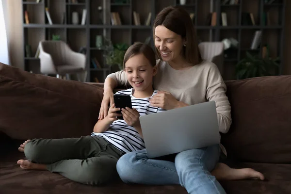 Chica feliz y mamá relajándose en el sofá con gadgets — Foto de Stock